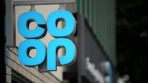 PA Media A hanging sign outside a shop showing the pale blue Co-op logo