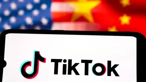 Getty Images TikTok logo is displayed on a smartphone screen, against a backdrop of the US and Chinese flags.