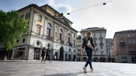AFP via Getty Images People walking in a central square in the Swiss city of Lugano