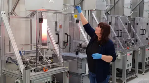 Kromek A technician wearing blue gloves adjusts one of a line of furnaces.