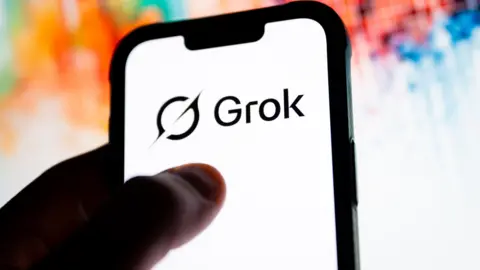 SOPA Images via Getty A phone with the Grok logo on it and a colourful background