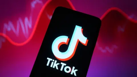 Getty Images TikTok logo shown on a smartphone against a backdrop illustrating rising and falling reports with a red line